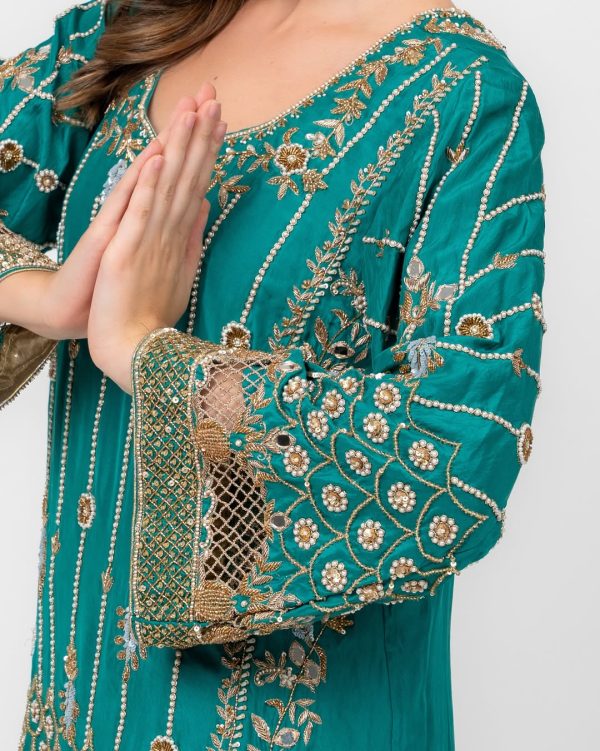 Detailed golden and beadwork embroidery on teal dress sleeve.