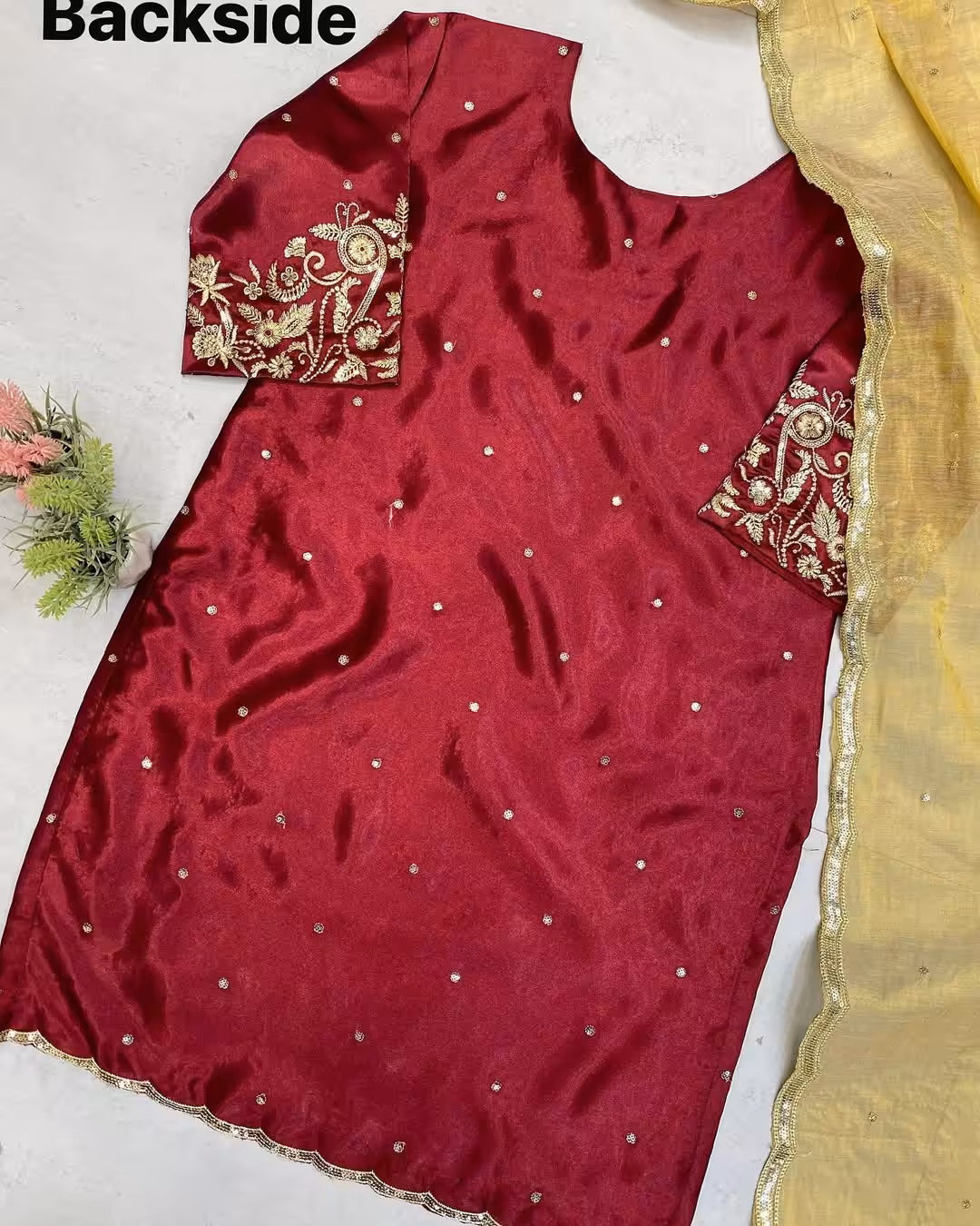 Back view: Embellished maroon ethnic dress with scattered gold motifs and ornate sleeve ends.