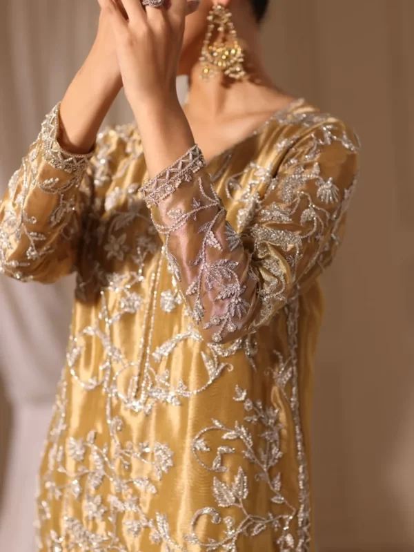 Detailed silver thread embroidery on golden silk fabric, showing sleeve and cuff design of a handcrafted ethnic dress.
