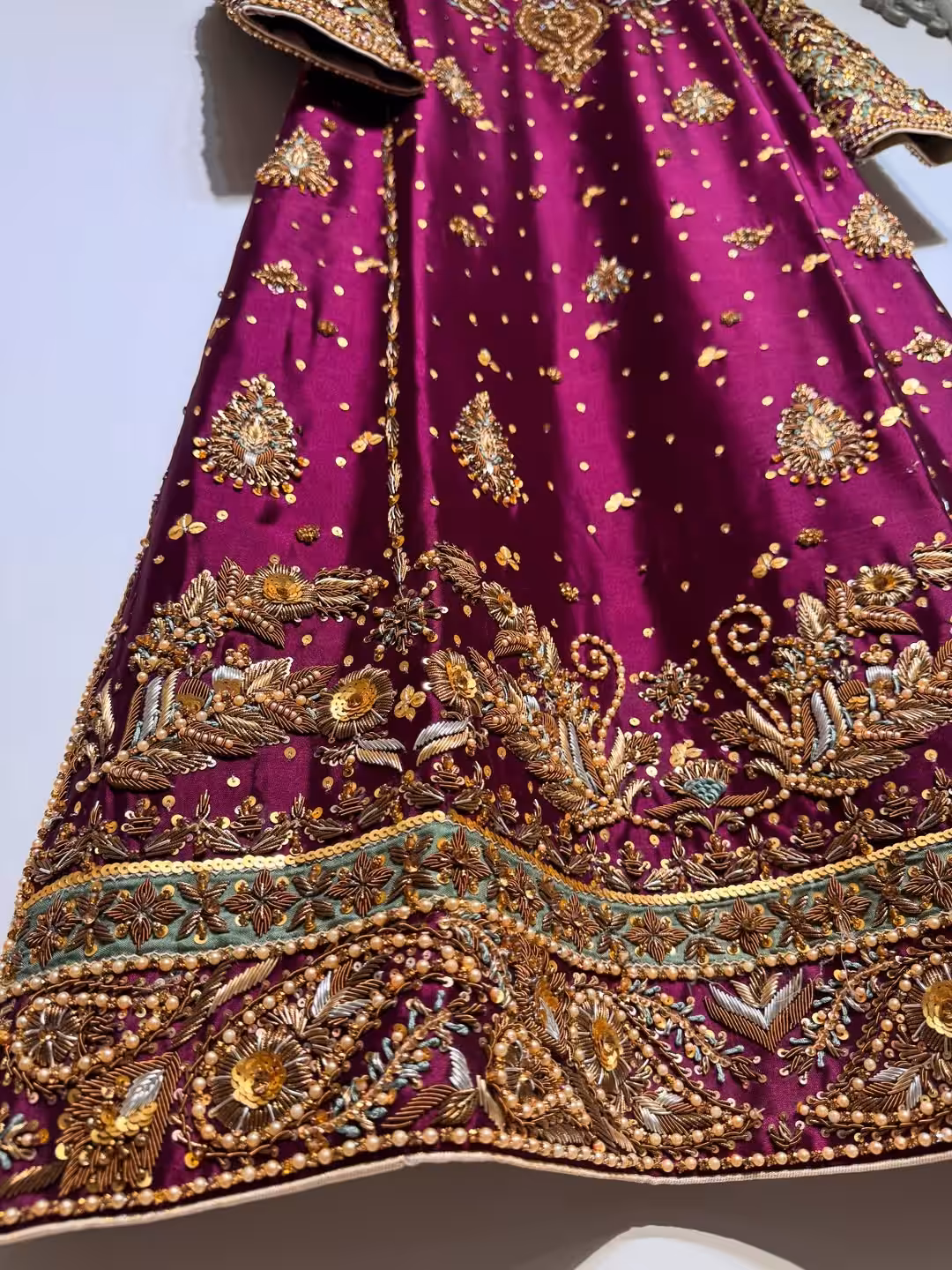 Ornate hand-embroidered lattice sleeve detail on maroon ethnic dress.