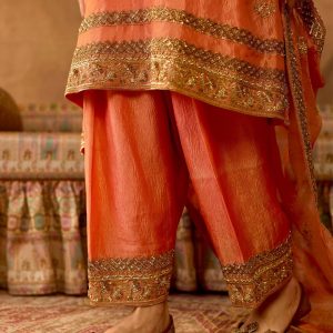 Closeup of embroidered borders and ankle of peach gold salwar suit set