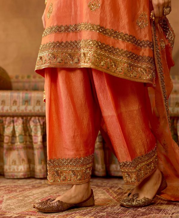 Closeup of embroidered borders and ankle of peach gold salwar suit set