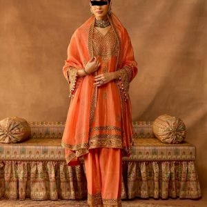 Model wearing peach gold embroidered salwar suit with matching dupatta and traditional jewelry