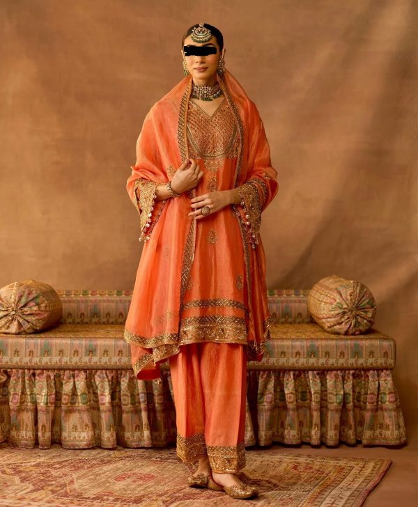 Model wearing peach gold embroidered salwar suit with matching dupatta and traditional jewelry